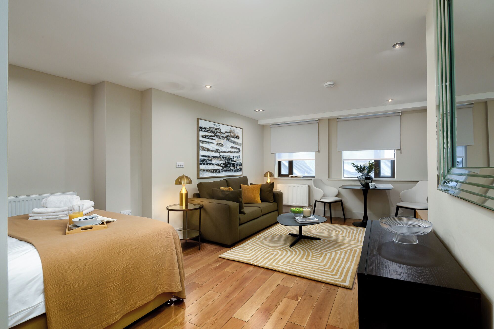 Een hotelkamer met een bed, een bank, een salontafel, een bureau en een stoel.
