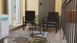 A small outdoor seating area with two chairs and a table, a potted plant, and a Hisense refrigerator.