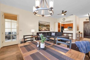 A modern living room with a dining table, sofa, and a view into the kitchen. - Heritage Hideaway A | 1BR Legacy Villa (La Quinta)