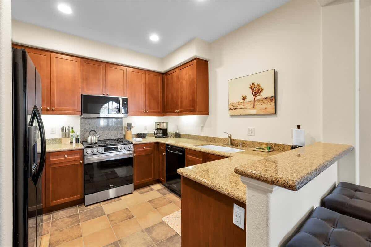 A kitchen with wooden cabinets, a stainless steel refrigerator, a microwave, a stove, and a dishwasher.