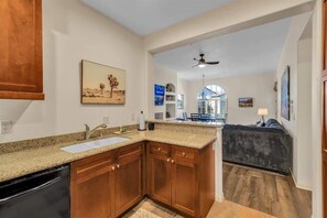 A kitchen with wooden cabinets, a granite countertop, and a dishwasher.