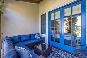 A blue sofa with cushions, a wicker coffee table, and a chair in a room with a patterned floor and a blue door.
