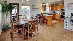 A spacious kitchen with wooden cabinets, a central island, and a dining area with a large table and chairs. - Inn at Dolphin Bay | Downtown, Garden View (Rockport)