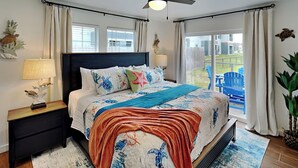 A bedroom with a large bed, a ceiling fan, and a view of the outdoors. - Inn at Dolphin Bay | Downtown, Garden View (Rockport)