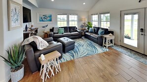 A spacious living room with a large sectional sofa, a wooden coffee table, and a patterned rug. - Inn at Dolphin Bay | Downtown, Garden View (Rockport)
