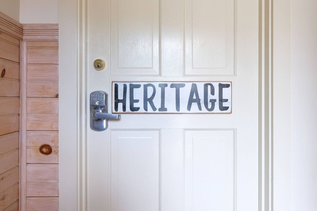 A white door with a metal handle and a sign that reads "HERITAGE".