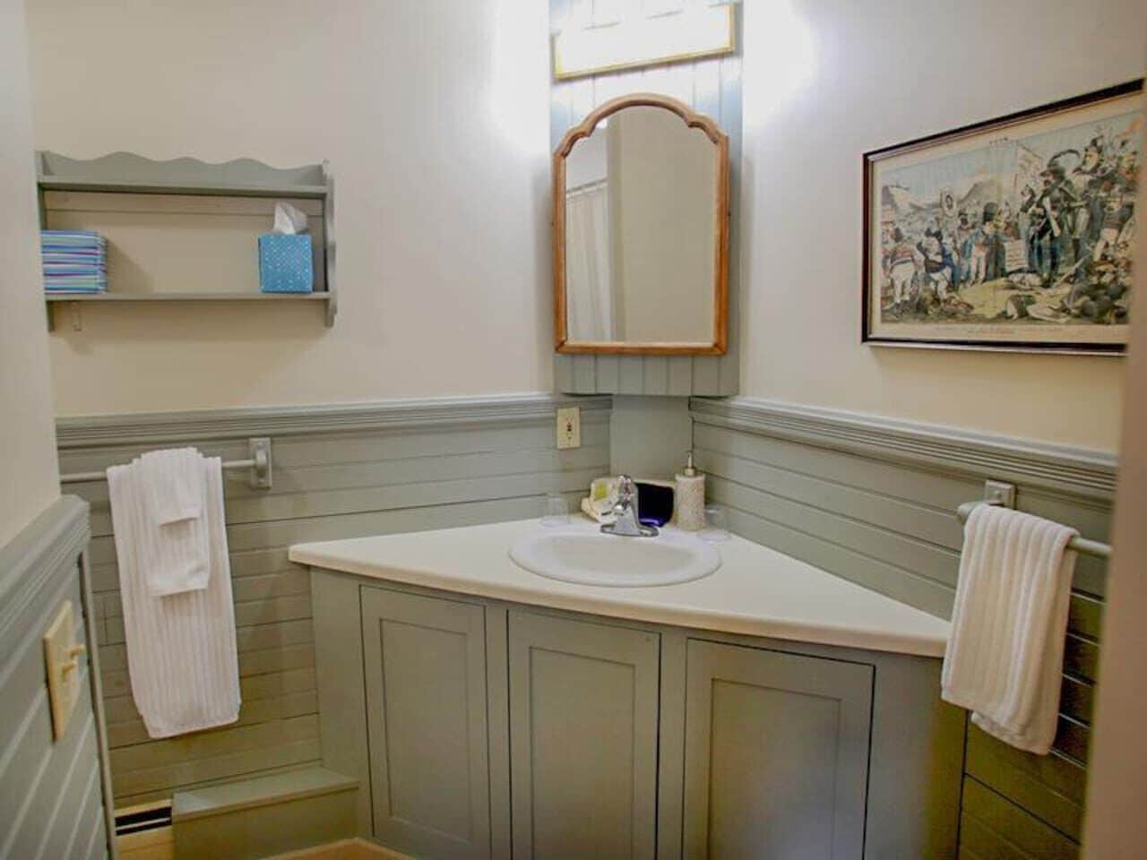 Uma casa de banho com lavatório, espelho, suporte para toalhas e um quadro na parede.