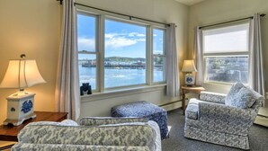 A hotel room with two beds, a sofa, and a view of a harbor. - Inn on the Harbor (Stonington)