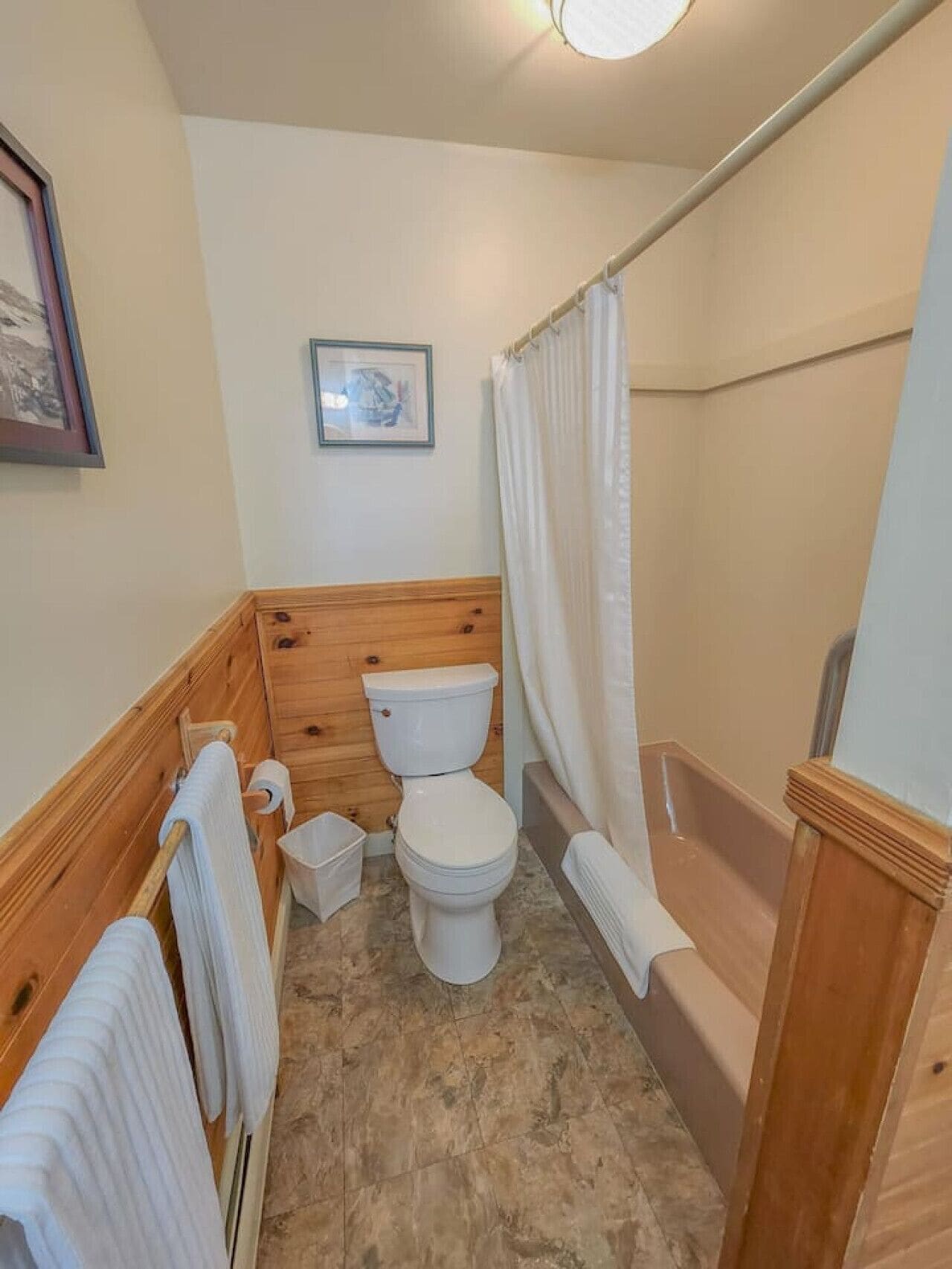 Un baño con tocador de madera, inodoro, bañera y cortina de ducha.