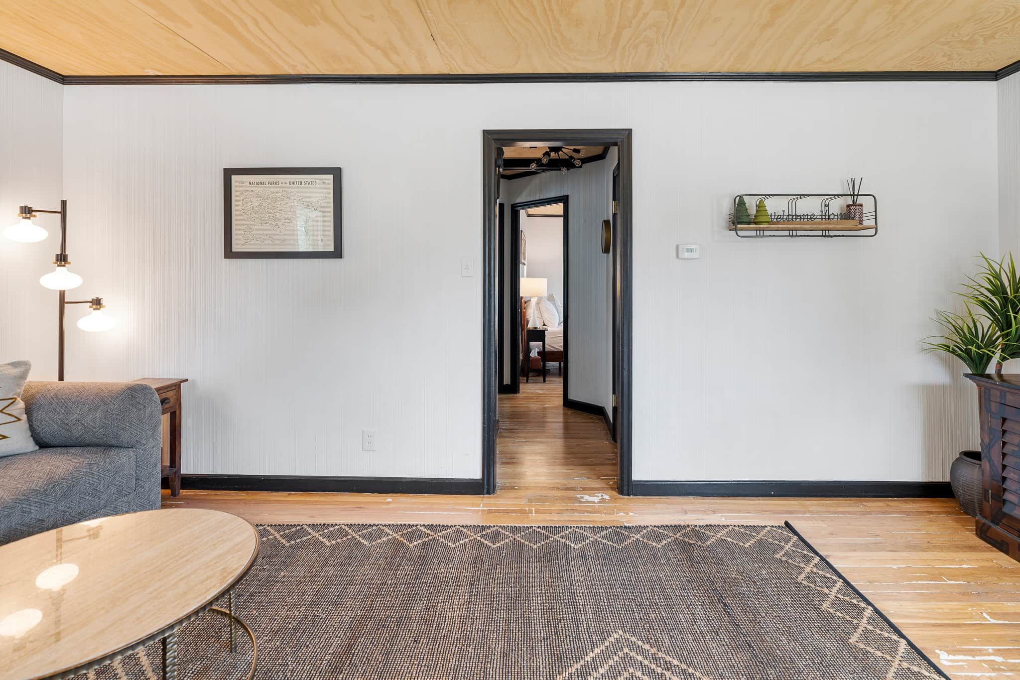 Una sala de estar moderna con un sofá, una mesa de centro, una alfombra, un aplique de pared y un mapa enmarcado.
