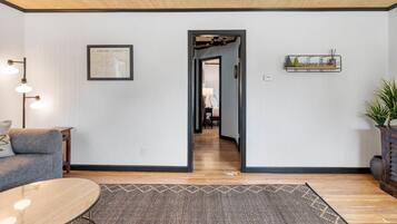Una sala de estar moderna con un sofá, una mesa de centro, una alfombra, un aplique de pared y un mapa enmarcado.