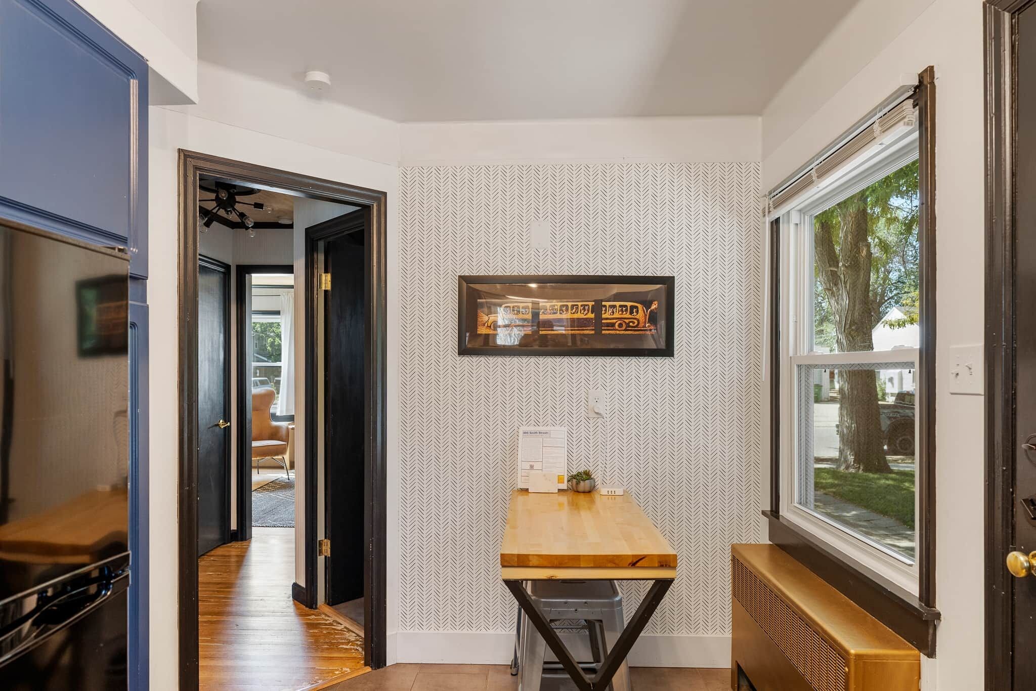 A hallway with a wooden table, a radiator, and a window with a view of the outdoors.