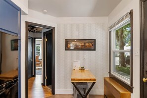 A hallway with a wooden table, a radiator, and a window with a view of the outdoors. - Stylish 1Br Near Main St | The Troubadour Suite (Sheridan)