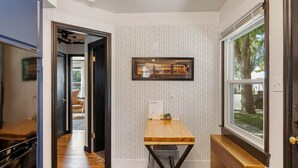 A hallway with a wooden table, a radiator, and a window with a view of the outdoors. - Stylish 1Br Near Main St | The Troubadour Suite (Sheridan)