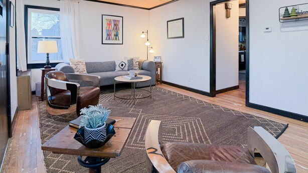 A modern living room with a sofa, coffee table, and chairs, a rug, and a framed picture on the wall. - Stylish 1Br Near Main St | The Troubadour Suite (Sheridan)