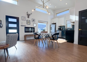 A modern interior with a dining area, kitchen, and a mounted deer head decoration.