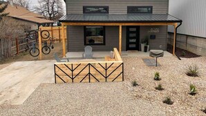 Una casa moderna con un porche cubierto, un aparcamiento para bicicletas y un camino de grava.