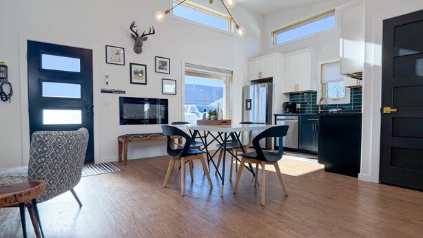 Un interior moderno con zona de comedor, cocina y una decoración con cabeza de venado.