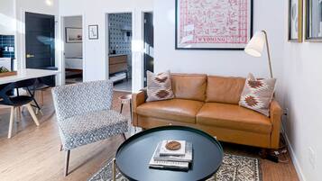 A modern living room with a leather sofa, patterned armchair, and a round coffee table.