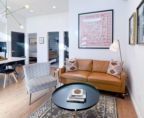A modern living room with a leather sofa, patterned armchair, and a round coffee table. - Fire Pit Under the Stars |The Wayfarer Bungalow (Sheridan)
