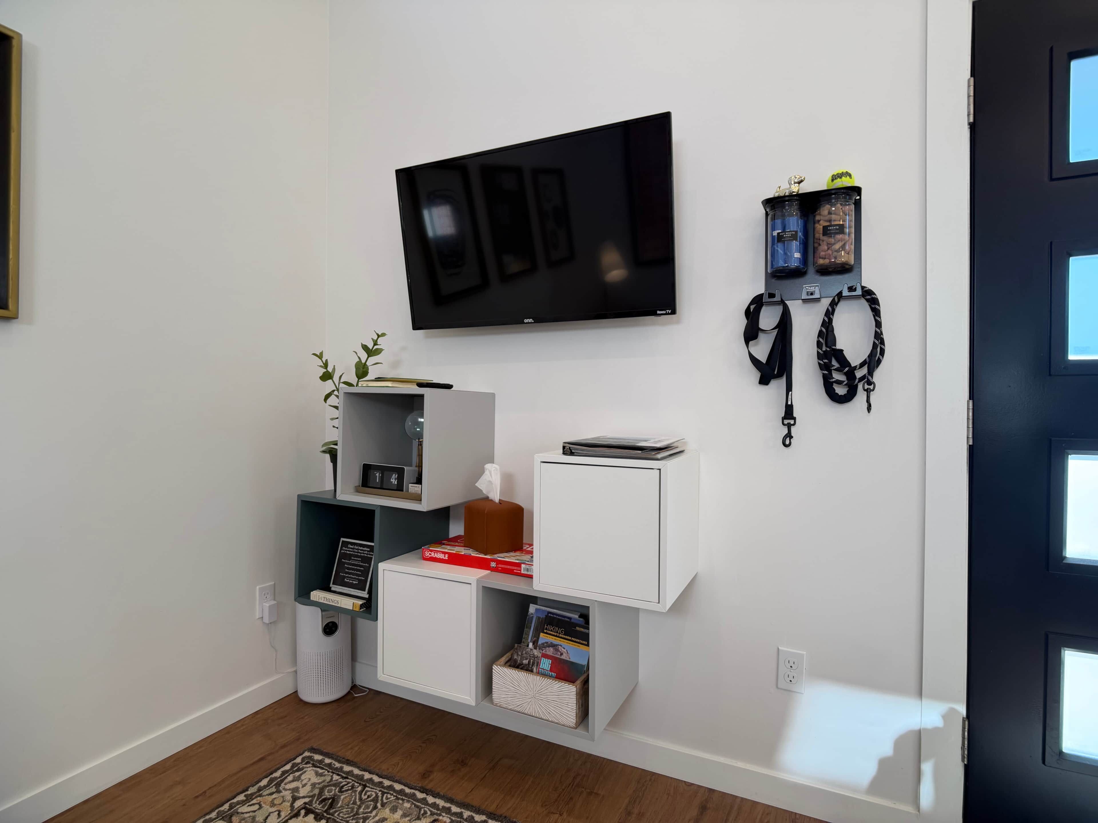 A modern living room with a flat-screen TV, a bookshelf, a small cabinet, and a door with a window.