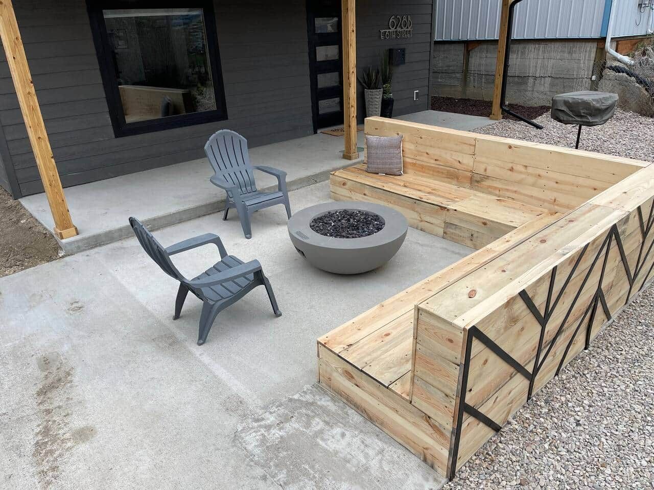 An outdoor seating area with a fire pit, two chairs, and a wooden bench.