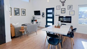 Una sala de estar moderna con comedor, televisor y cabeza de venado montada.