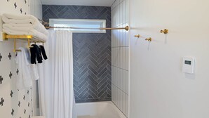 Un baño con bañera, inodoro y un perchero con toallas dobladas.