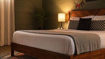 A neatly made bed with a wooden headboard, a bedside lamp, and a patterned rug on the floor.