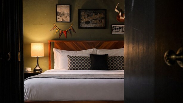 Ein Hotelzimmer mit einem Bett, einem Nachttisch mit Lampe und einer Wand mit gerahmten Bildern.