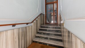Eine Marmortreppe mit einem hölzernen Geländer, das zu einer Glastür führt.