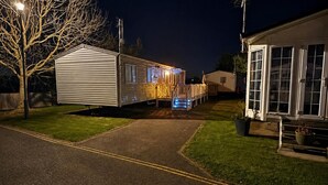 Une maison mobile dotée d’un porche et d’un éclairage extérieur, d’une allée pavée et d’une pelouse.