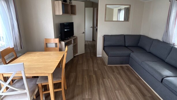 Un espace de vie compact comprenant une table à manger, des chaises, un canapé, un téléviseur et un miroir.