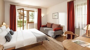 Une chambre d’hôtel équipée d’un lit, d’un canapé, d’une table à manger et offrant une vue sur l’extérieur.