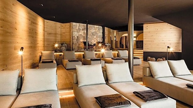 Un intérieur moderne avec des canapés disposés en demi-cercle, des murs en bois et un éclairage d’ambiance.