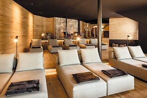 Ein modernes Interieur mit in Halbkreis angeordneten Sofas, Holzwänden und stimmungsvoller Beleuchtung.