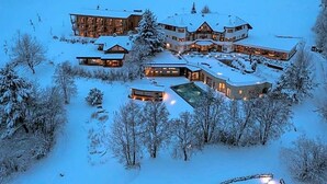 Ein großes, mehrstöckiges Gebäude mit schneebedecktem Dach und umliegenden Bäumen.