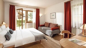 Une chambre d’hôtel équipée d’un lit, d’un canapé, d’une table à manger et offrant une vue sur l’extérieur.