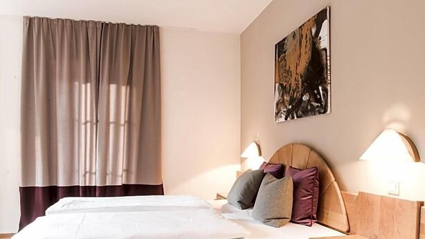 Une chambre d’hôtel avec un lit, deux lampes de chevet, une tête de lit et un tableau au mur.