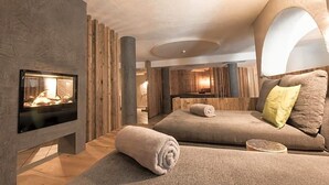 Un espace spa moderne doté d’une cheminée, de murs en bois et d’un coin salon confortable.