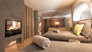 Un espace spa moderne doté d’une cheminée, de murs en bois et d’un coin salon confortable.