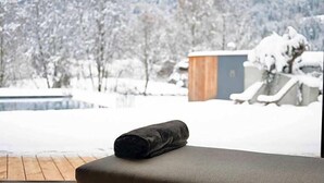 Une pièce avec vue sur un paysage enneigé, une terrasse en bois et un petit abri de jardin.