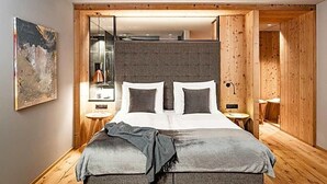 Une chambre moderne avec un grand lit, un plancher en bois et une tête de lit grise.