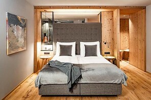 Une chambre moderne avec un grand lit, un plancher en bois et une tête de lit grise.