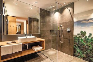 Een moderne badkamer met een glazen douchecabine, een houten wastafelmeubel en een grote spiegel.
