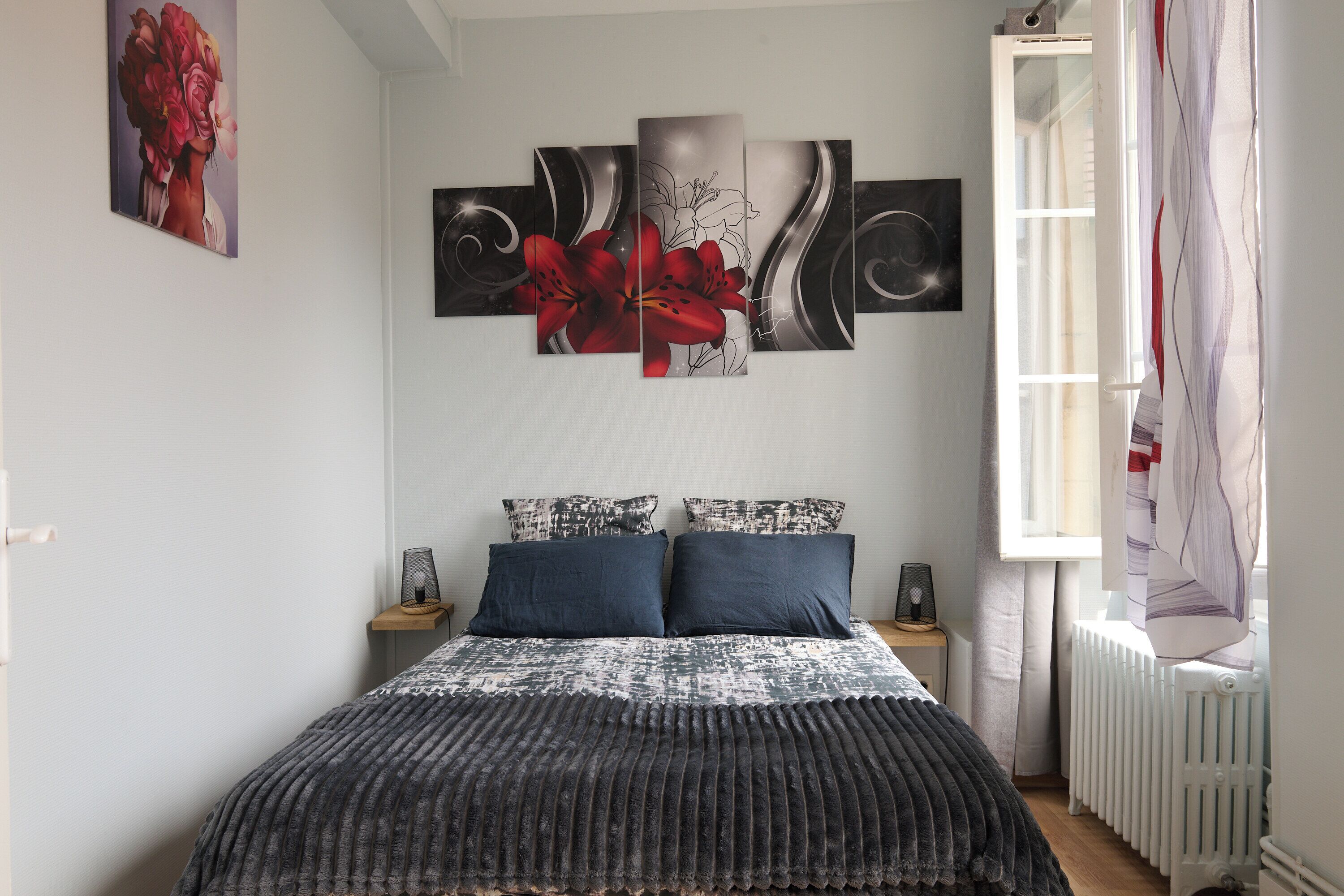 A bedroom with a bed, two nightstands, a radiator, and a window with curtains.