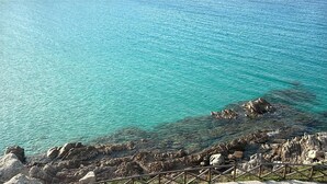 Un paisaje costero con aguas turquesas cristalinas y terreno rocoso.