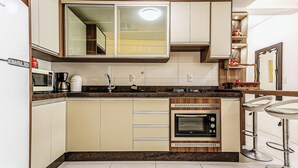 A compact kitchen with a microwave, coffee maker, and built-in oven.