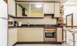Cozinha compacta com micro-ondas, cafeteira e forno embutido.