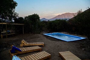 A backyard with a swimming pool, wooden lounge chairs, and a pergola. - Cabañas Ocoa (Hijuelas)